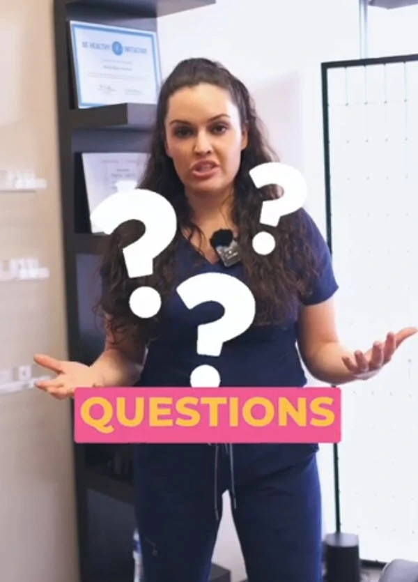 Paramedical tattoo artist addressing frequently asked questions, wearing navy scrubs with a mic, standing in a professional studio with question marks overlay.