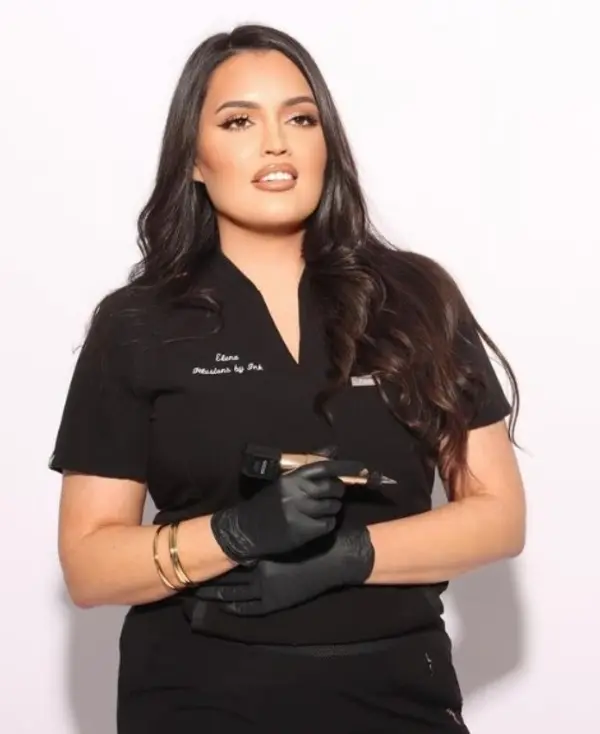 Master paramedical tattoo artist Elena Sanchez holding a tattoo pen, specializing in scar camouflage and skin tone restoration at Illusions by Ink Studio.