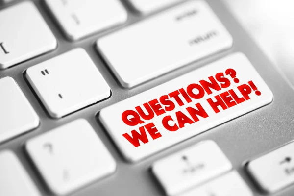 White keyboard with a key labeled 'QUESTIONS? WE CAN HELP!' in bold red text, symbolizing customer support and assistance.