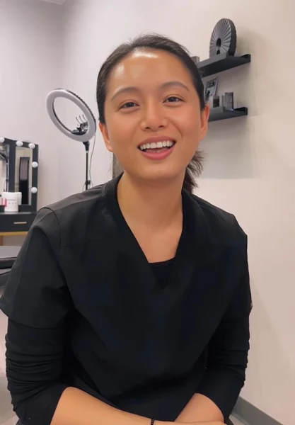 Bidya, a 3D tattoo specialist at Illusions by Ink Studio, smiling during a client consultation inside the treatment room.